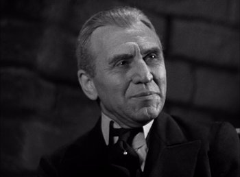 Movie still from “Frankenstein” (1931), directed by James Whale – An older man wearing a suit and tie; Close Up shot, Low angle