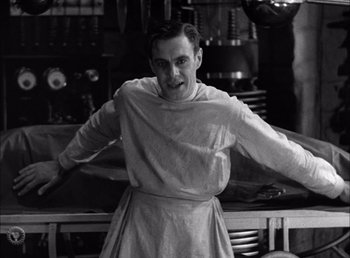 Movie still from “Frankenstein” (1931), directed by James Whale – A black and white photo of a man in a kitchen; Medium shot, Low angle