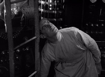 Movie still from “Frankenstein” (1931), directed by James Whale – A black and white photo of a man leaning against a wall; Medium shot, Low angle