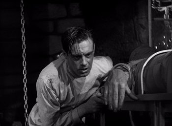 Movie still from “Frankenstein” (1931), directed by James Whale – A black and white photo of a man leaning on a railing; Medium shot, Low angle