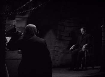 Movie still from “Frankenstein” (1931), directed by James Whale – A man taking a picture of a man sitting in a chair; Wide shot, Over the shoulder angle