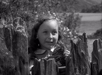 Movie still from “Frankenstein” (1931), directed by James Whale – A little girl standing next to a wooden fence; Medium shot, High angle