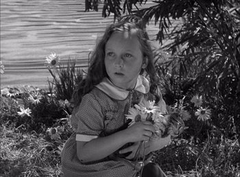 Movie still from “Frankenstein” (1931), directed by James Whale – A little girl sitting in the grass holding flowers; Close Up shot, High angle