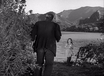 Movie still from “Frankenstein” (1931), directed by James Whale – A man and a little girl standing next to a body of water; Wide shot, Over the shoulder angle