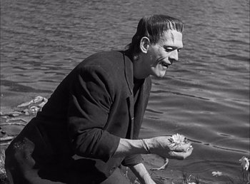 Movie still from “Frankenstein” (1931), directed by James Whale – A black and white photo of a man holding a flower; Medium shot, Over the shoulder angle