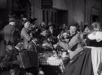 Movie still from “Frankenstein” (1931), directed by James Whale – A group of people sitting at a table with food; Wide shot, Low angle