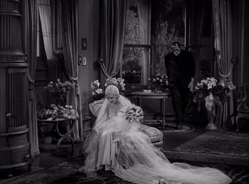 Movie still from “Frankenstein” (1931), directed by James Whale – A woman in a wedding dress sitting on a chair; Wide shot, High angle