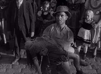 Movie still from “Frankenstein” (1931), directed by James Whale – An old photo of a man carrying a child; Medium shot, High angle