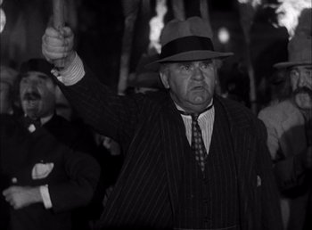 Movie still from “Frankenstein” (1931), directed by James Whale – An older man in a hat and a suit holding a stick; Medium shot, Low angle