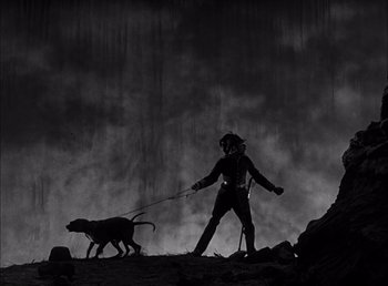 Movie still from “Frankenstein” (1931), directed by James Whale – A man and a dog are walking in the dark; Wide shot, Low angle