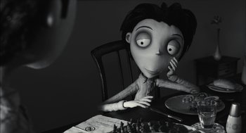 Movie still from “Frankenweenie” (2012), directed by Tim Burton – A black - and - white photo of a person sitting at a table; Close Up shot, Over the shoulder angle