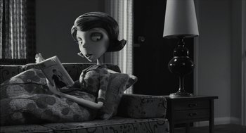 Movie still from “Frankenweenie” (2012), directed by Tim Burton – A woman sitting on a couch reading a book; Medium shot, Over the shoulder angle