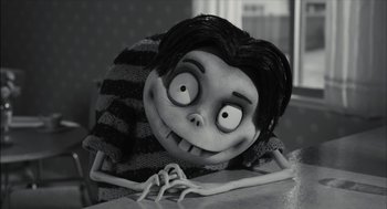 Movie still from “Frankenweenie” (2012), directed by Tim Burton – A creepy doll is sitting on a table; Medium shot, High angle