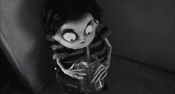 Movie still from “Frankenweenie” (2012), directed by Tim Burton – A black and white photo of a doll holding a drink; Medium shot, High angle