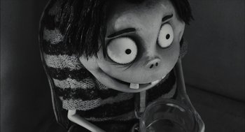 Movie still from “Frankenweenie” (2012), directed by Tim Burton – A creepy doll is sitting next to a glass; Close Up shot, High angle