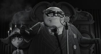 Movie still from “Frankenweenie” (2012), directed by Tim Burton – A black and white photo of a person with a microphone; Medium shot, Low angle
