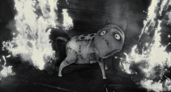 A black and white photo of a dog statue with burning flames in the background