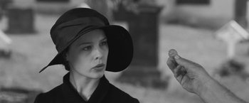 Movie still from “Frantz” (2016), directed by François Ozon – A woman wearing a black hat holding a piece of food; Close Up shot, Over the shoulder angle
