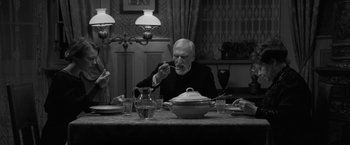 Movie still from “Frantz” (2016), directed by François Ozon – An older man sitting at a table with a bowl of food; Medium shot, High angle