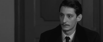 Movie still from “Frantz” (2016), directed by François Ozon – A black and white photo of a man in a suit and tie; Close Up shot, Over the shoulder angle
