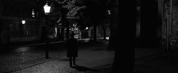 Movie still from “Frantz” (2016), directed by François Ozon – A person standing in the dark near a tree; Wide shot, Over the shoulder angle