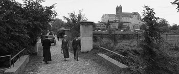 Movie still from “Frantz” (2016), directed by François Ozon – A man and a woman walking down a brick path; Wide shot, High angle