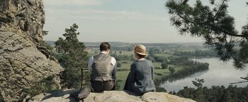 Movie still from “Frantz” (2016), directed by François Ozon – A man and a woman sitting on top of a cliff; Wide shot, High angle