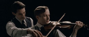 Movie still from “Frantz” (2016), directed by François Ozon – A man playing a violin while another man plays the violin; Close Up shot, Low angle