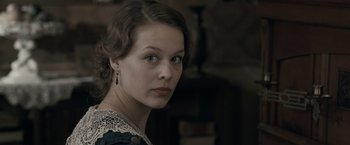 Movie still from “Frantz” (2016), directed by François Ozon – A young woman in a black and white dress looking at the camera; Close Up shot, Over the shoulder angle