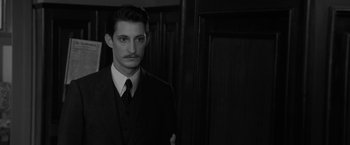 Movie still from “Frantz” (2016), directed by François Ozon – A man in a suit and tie standing in front of a wooden wall; Close Up shot, Over the shoulder angle