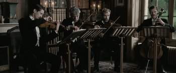 Movie still from “Frantz” (2016), directed by François Ozon – A group of people playing musical instruments in a room; Medium shot, Low angle