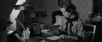 Movie still from “Frantz” (2016), directed by François Ozon – A woman sitting at a table writing on a piece of paper; Medium shot, High angle
