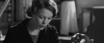 Movie still from “Frantz” (2016), directed by François Ozon – A woman sitting in front of a table looking down; Close Up shot, Over the shoulder angle