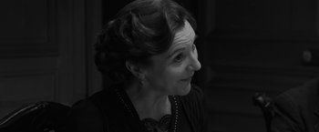 Movie still from “Frantz” (2016), directed by François Ozon – An older woman wearing a necklace and a black top; Close Up shot, Over the shoulder angle