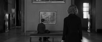 Movie still from “Frantz” (2016), directed by François Ozon – Two people are sitting on a bench in front of a painting; Medium shot, Over the shoulder angle