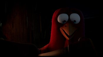 Movie still from “Free Birds” (2013), directed by Jimmy Hayward – A red bird with blue eyes sitting in a dark room; Close Up shot, High angle