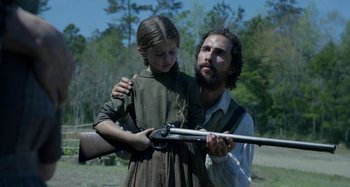 Movie still from “Free State of Jones” (2016), directed by Gary Ross – A man and a little girl with a gun; Medium shot, Over the shoulder angle