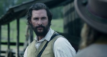 Movie still from “Free State of Jones” (2016), directed by Gary Ross – A man with long hair and a beard standing in a field; Close Up shot, Over the shoulder angle