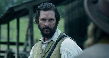 Movie still from “Free State of Jones” (2016), directed by Gary Ross – A man with long hair and a beard standing in a field; Close Up shot, Over the shoulder angle