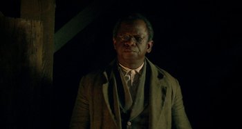 Movie still from “Free State of Jones” (2016), directed by Gary Ross – A man in a suit standing in a dark room; Close Up shot, Low angle