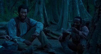Movie still from “Free State of Jones” (2016), directed by Gary Ross – Two men sitting on the ground in the woods at night; Medium shot, Over the shoulder angle