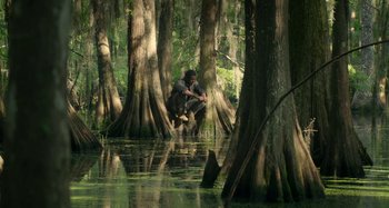 Movie still from “Free State of Jones” (2016), directed by Gary Ross – A man crouching in the middle of a forest; Extreme Wide shot, High angle