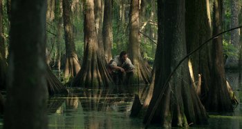 Movie still from “Free State of Jones” (2016), directed by Gary Ross – A man sitting in the middle of a forest; Extreme Wide shot, Low angle