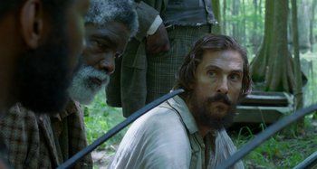 Movie still from “Free State of Jones” (2016), directed by Gary Ross – A man with a beard is sitting on the ground with another man; Close Up shot, Over the shoulder angle