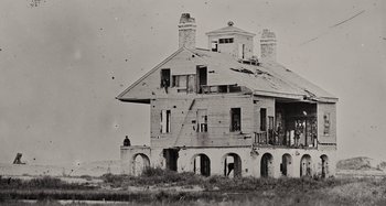 Movie still from “Free State of Jones” (2016), directed by Gary Ross – An old photo of an abandoned house with a person sitting on the porch; Extreme Wide shot, Low angle