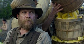 Movie still from “Free State of Jones” (2016), directed by Gary Ross – A man with a beard wearing a hat and a vest; Close Up shot, Over the shoulder angle