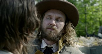 Movie still from “Free State of Jones” (2016), directed by Gary Ross – A man with long hair and a beard wearing a hat; Close Up shot, Over the shoulder angle