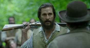 Movie still from “Free State of Jones” (2016), directed by Gary Ross – A man with a beard holding a rifle in his hand; Close Up shot, Over the shoulder angle