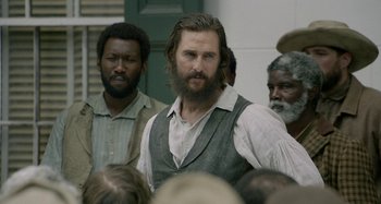 Movie still from “Free State of Jones” (2016), directed by Gary Ross – A group of men standing next to each other in front of a building; Close Up shot, Over the shoulder angle