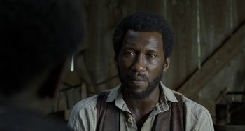 Movie still from “Free State of Jones” (2016), directed by Gary Ross – A black man with a beard and a vest; Close Up shot, Over the shoulder angle